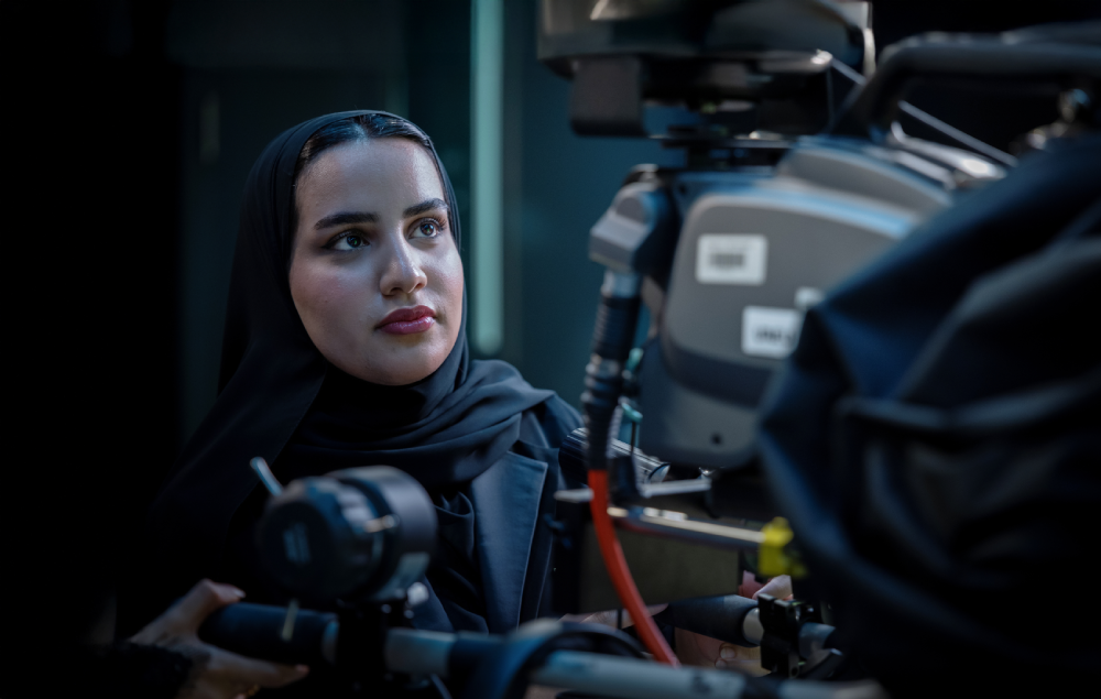 A female student operating a professional cinema camera in a studio.