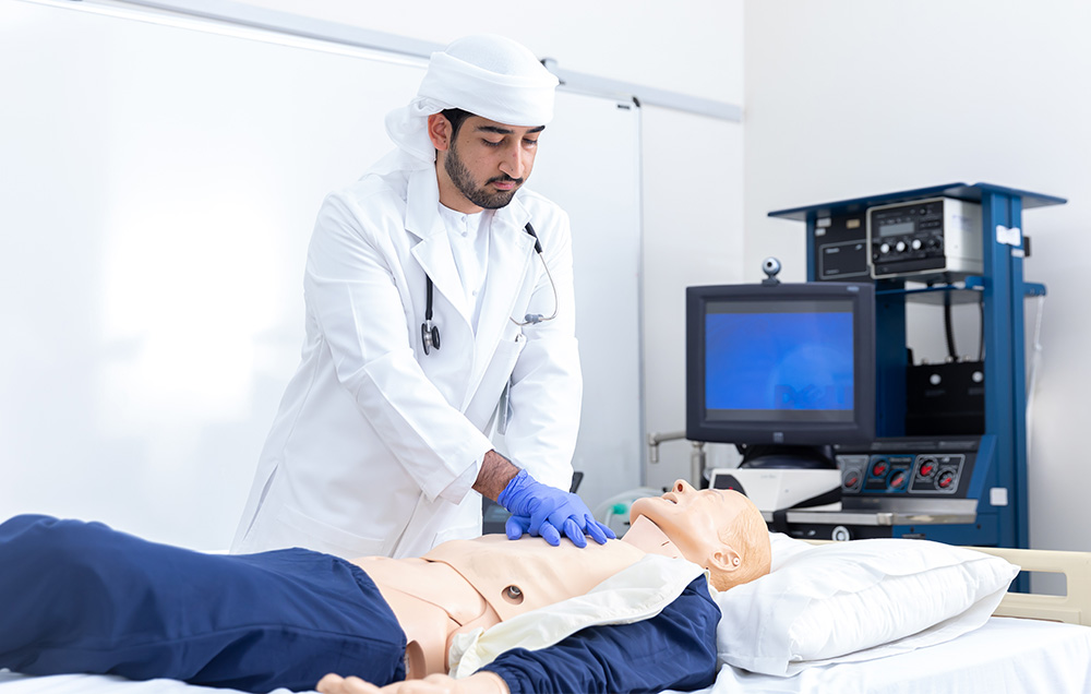 Doctor performing CPR training on a medical mannequin in a clinical training room.