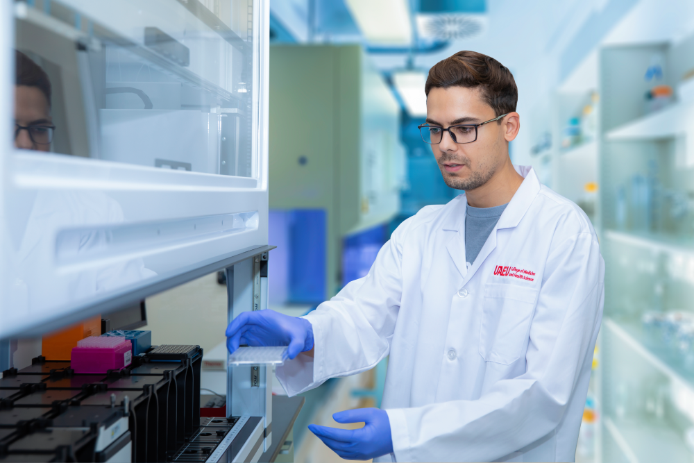 UAEU College of Medicine and Health Sciences handling a microplate in a high-tech laboratory