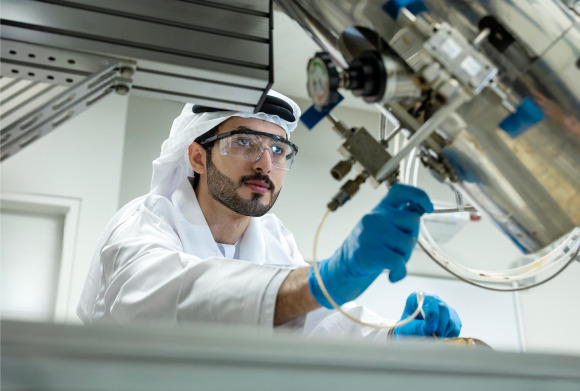 UAEU student in safety gear working with lab equipment.